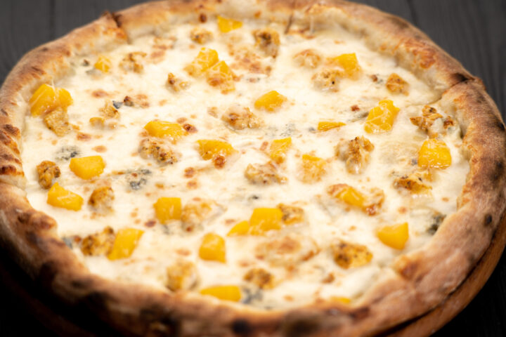 Sweet Gorgonzola pizza with honey and peach on wooden table, close up