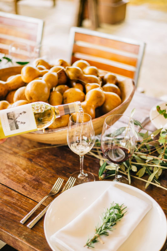 Fresh pears and a glass of white wine on a rustic wooden table at Round Pond Estate.