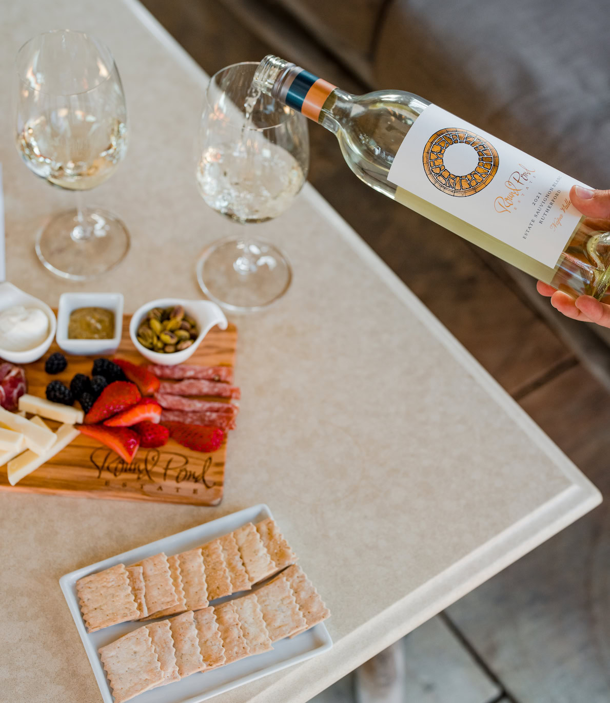 Elegant wine pouring at Round Pond Estate with glasses, charcuterie, and fresh fruit for tasting.