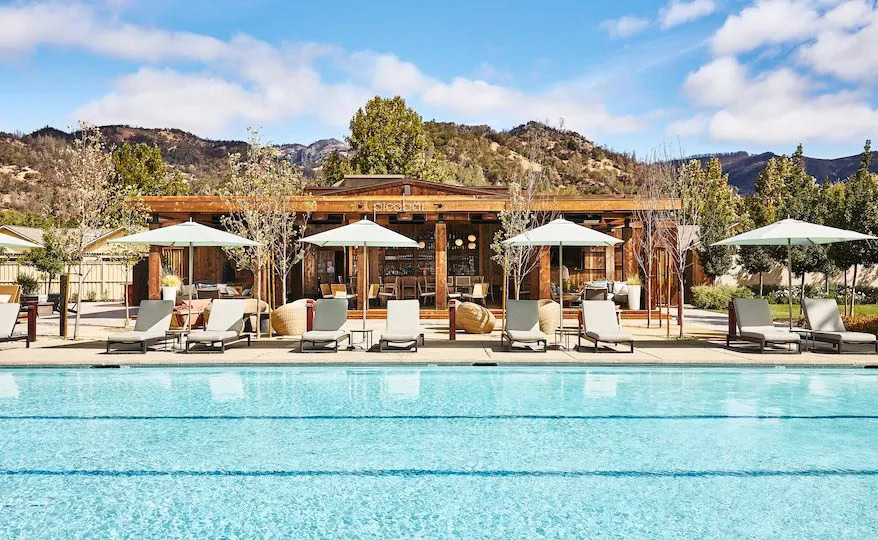 Poolside lounge with umbrellas at Round Pond Estate in Napa Valley, offering a relaxing setting amidst scenic vineyard views.