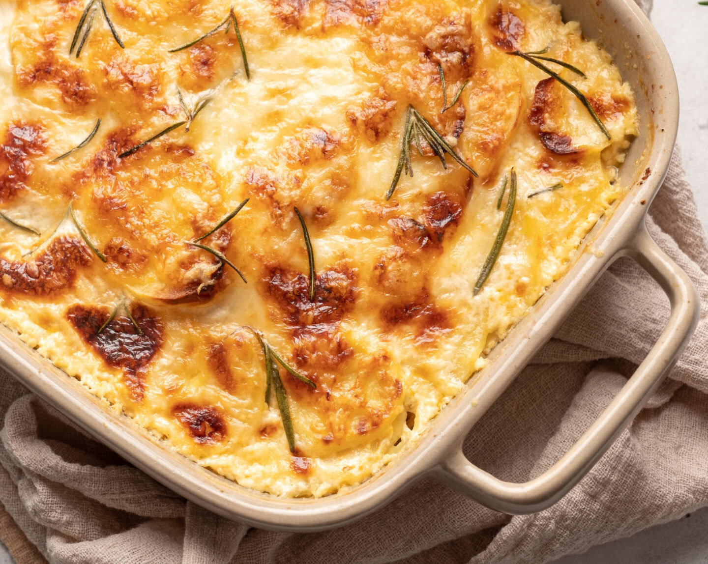 Creamy chicken and herb casserole baked with cheese and fresh rosemary, served in a white baking dish.