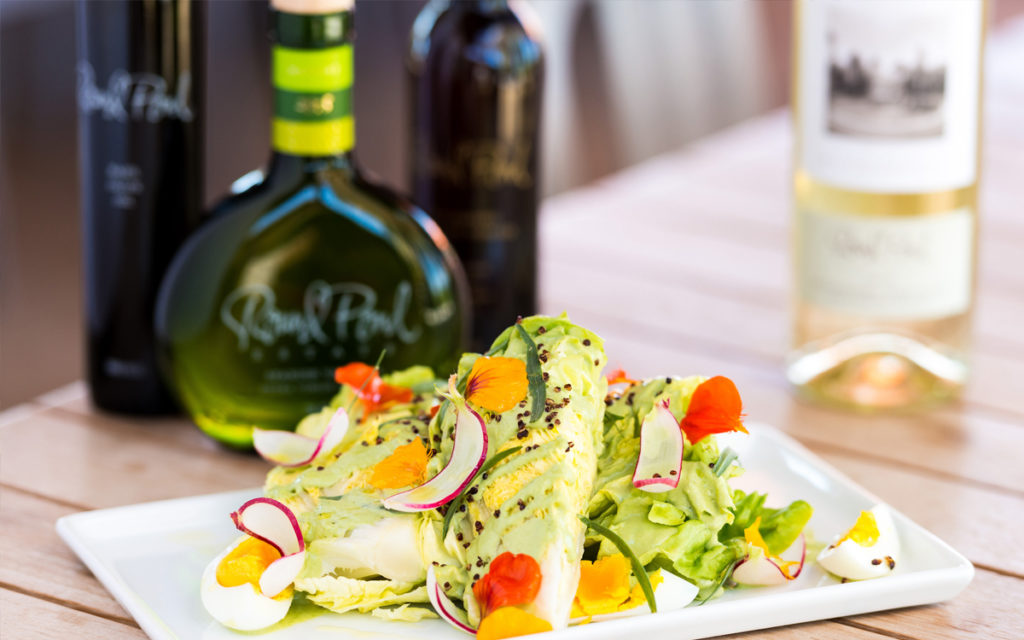 Green Goddess Salad with a bottle of olive oil and wine
