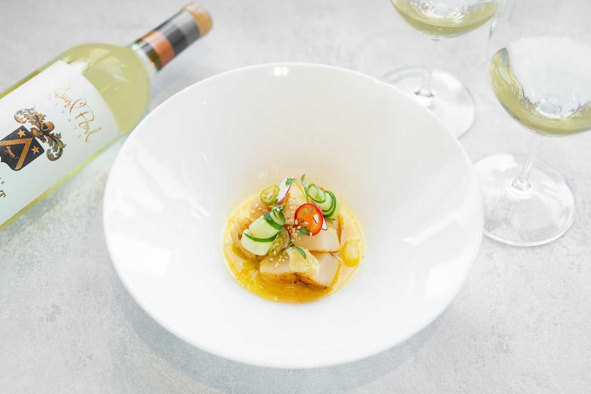 Elegant wine and gourmet dish pairing at Round Pond Estate, showcasing farm-to-table freshness with a glass of white wine.