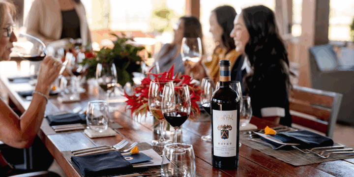 Guests gather a table with wine in hand. Louis Bovet Reserve Cabernet Sauvignon stands strong at the head of the table.