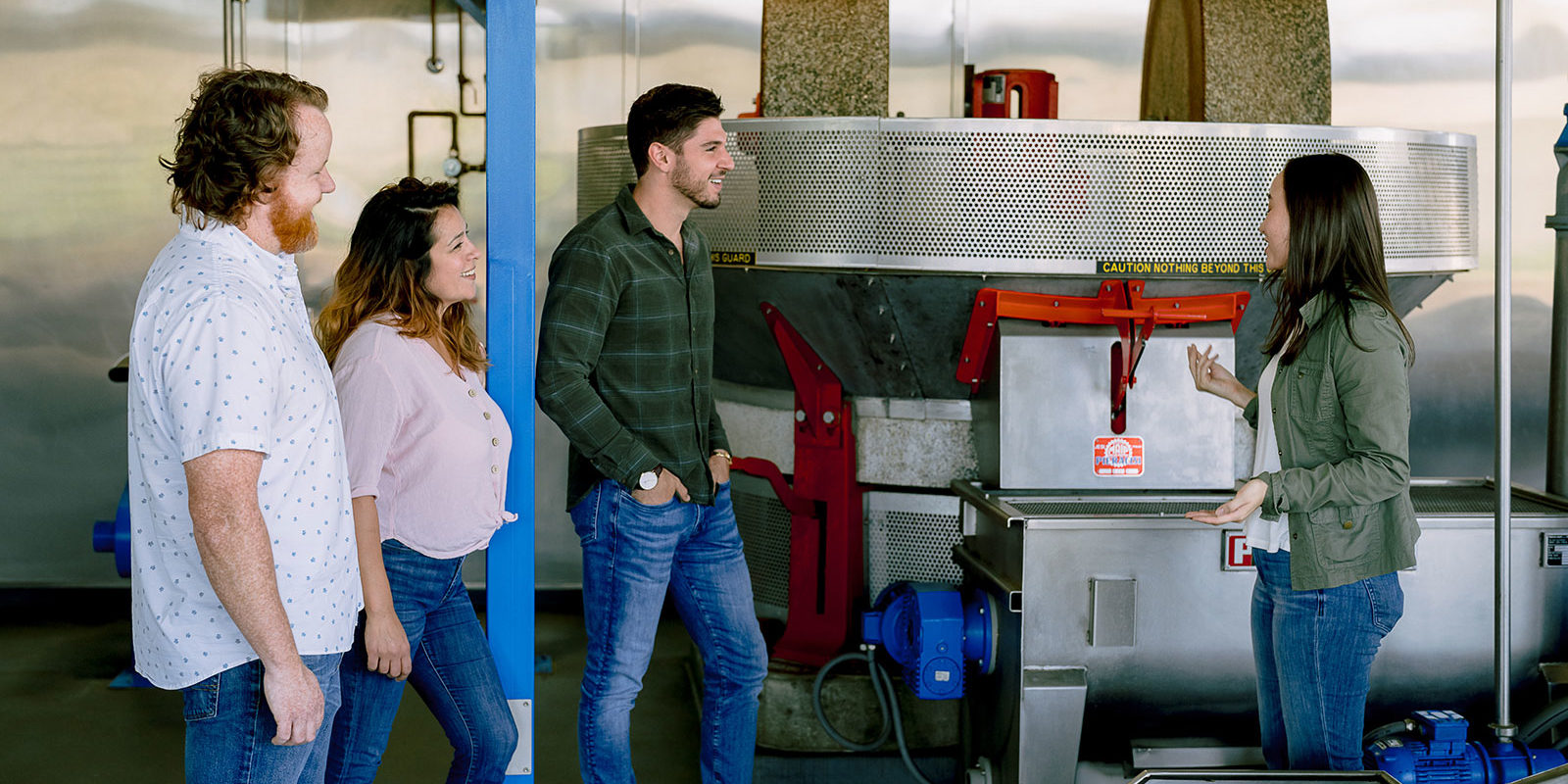 Group of four people standing in front of a stone olive press