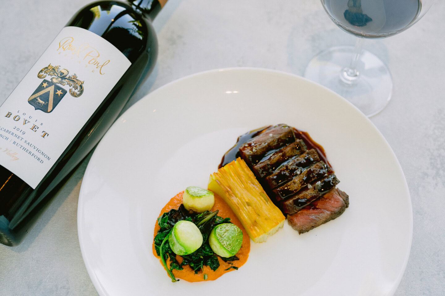 Luxurious Napa Valley cuisine featuring a glass of red wine, steak, and fresh vegetables.