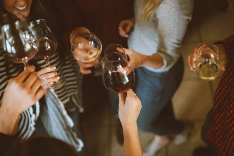 Many hands holding red and white wine glasses