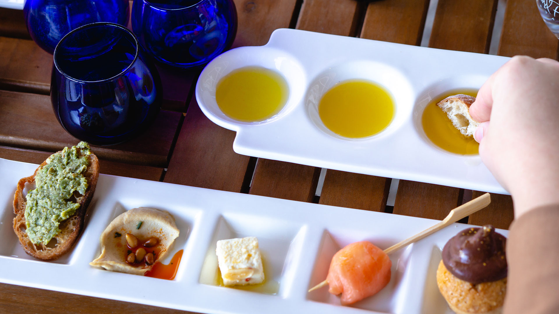 Olive oil tasting setup with three small bowls of olive oil, bread, and accompaniments at Round Pond Estate.