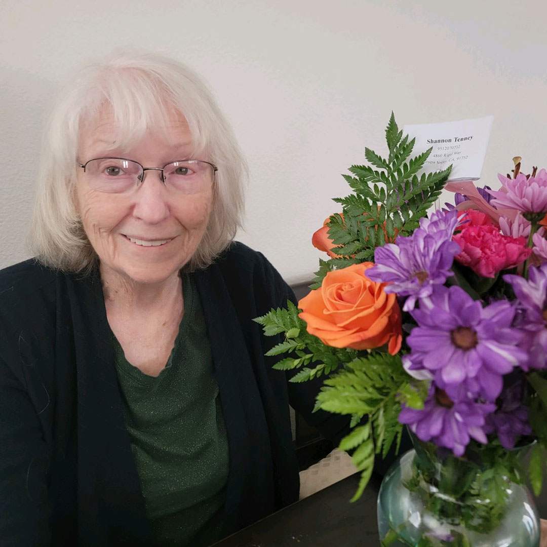 Elderly woman smiling with a colorful bouquet of flowers.