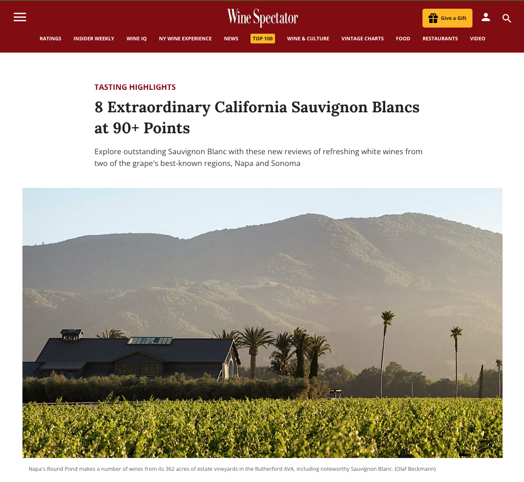Vineyard at Round Pond Estate with rolling hills and palm trees in Napa Valley, California, under a clear sky.