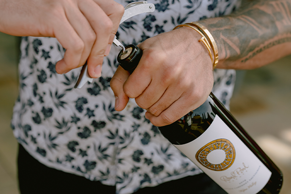 Person opening a bottle of wine at Round Pond Estate vineyard in Napa Valley.
