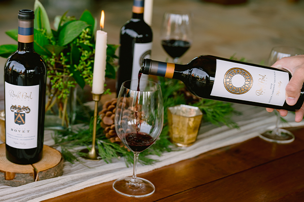 Pouring red wine into a glass at a vineyard tasting table.