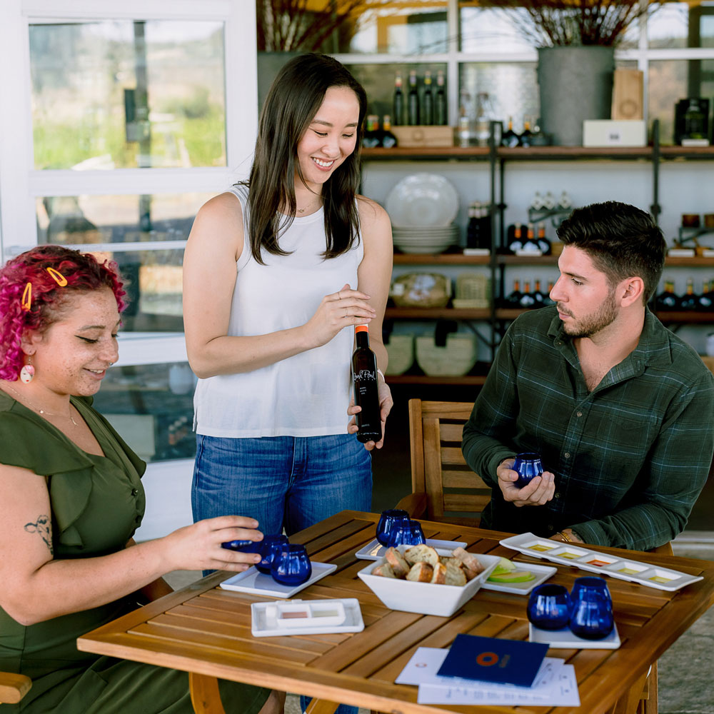 Woman presenting olive oil tasting to two guests at Round Pond Estate, Napa Valley.