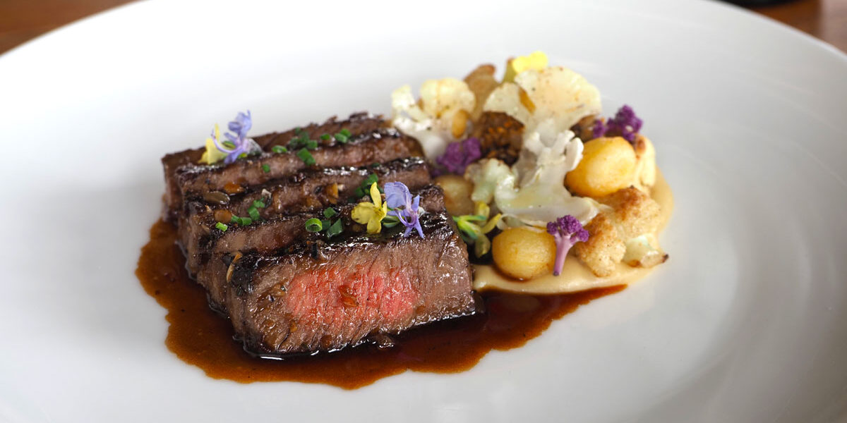 A sliced ribeye on a plate with juices.