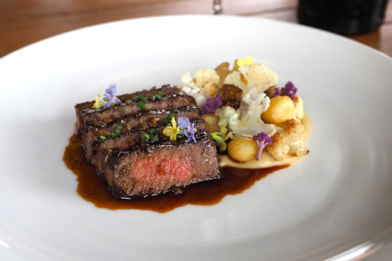 A sliced ribeye on a plate with juices.