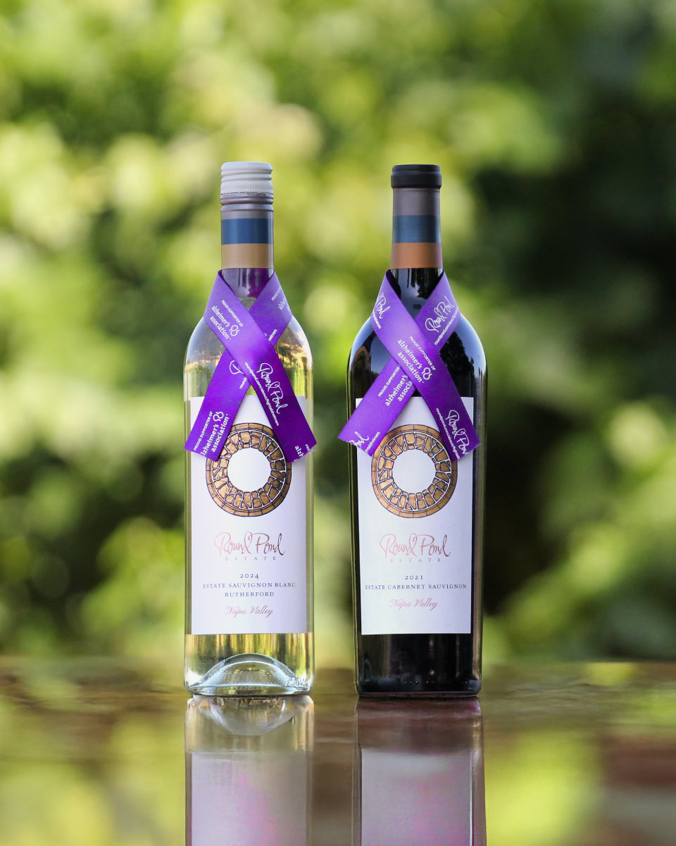 Two bottles of wine from Round Pond Estate, one white and one red, displayed outdoors with a blurred green background.