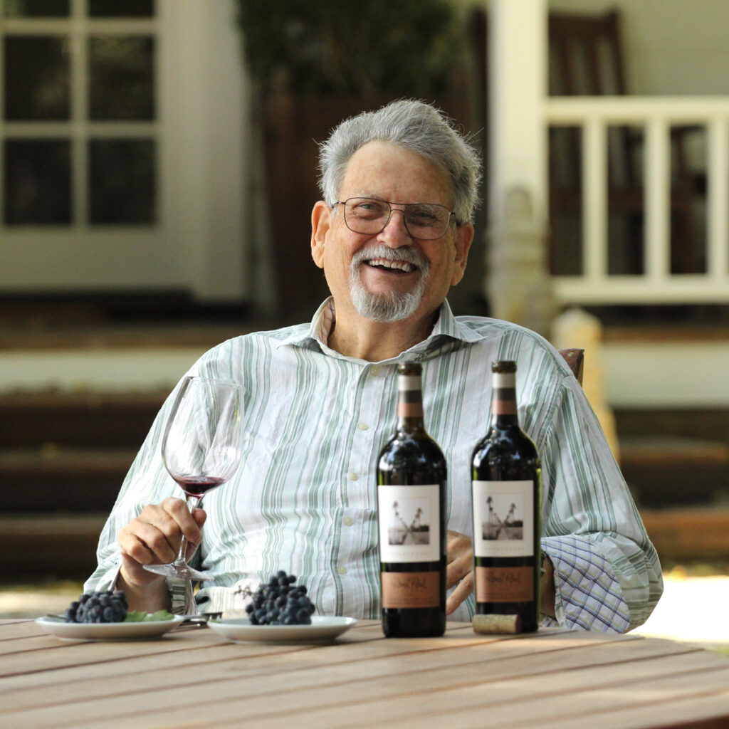 Round Pond Estate's Sommelier, Scott Tracy, smiling while sitting at a table with a glass of red wine.