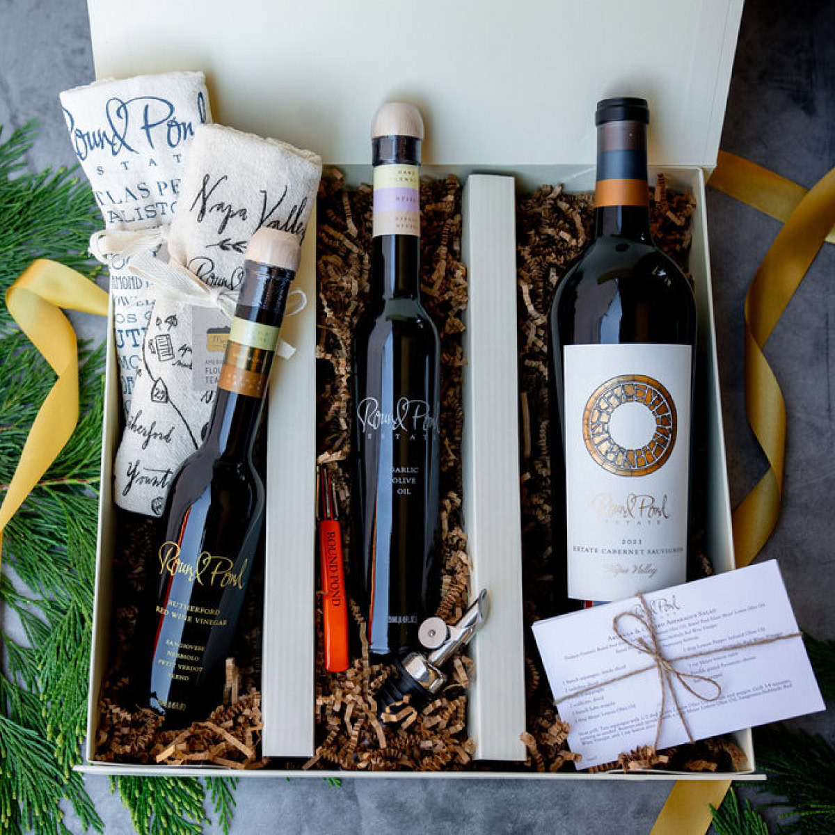 Elegant wine gift set from Round Pond Estate with bottles, accessories, and handwritten notes in a gift box.