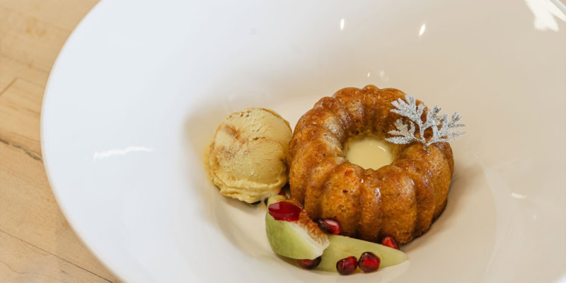 Carrot Bundt cake served with ice cream, garnished with pomegranate seeds and apple slices.