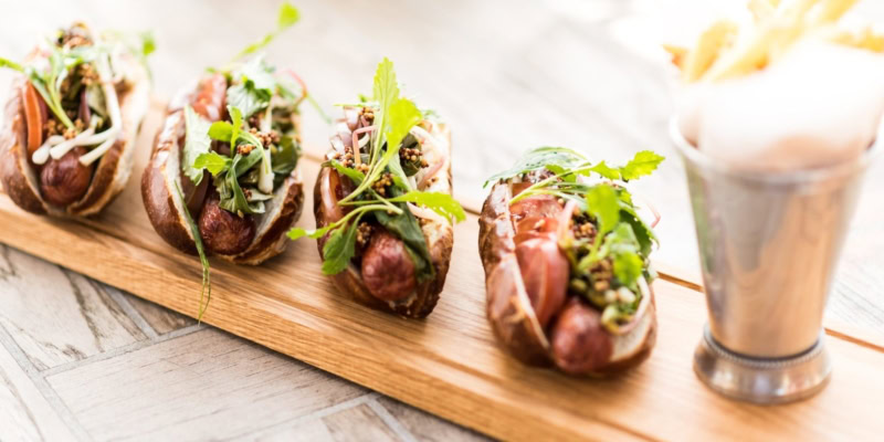 Delicious Napa-style Chicago hot dogs with fresh toppings on a wooden serving board.