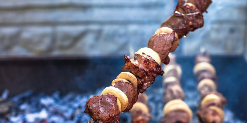 Close-up of grilled marinated lamb skewers on a barbecue grill.