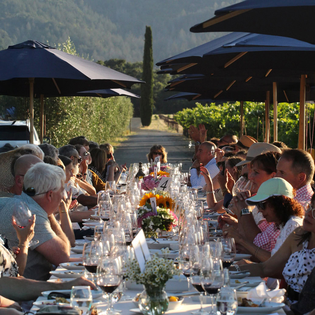 Alfresco dinner setup with guests enjoying a sunset meal under umbrellas at Round Pond Estate.