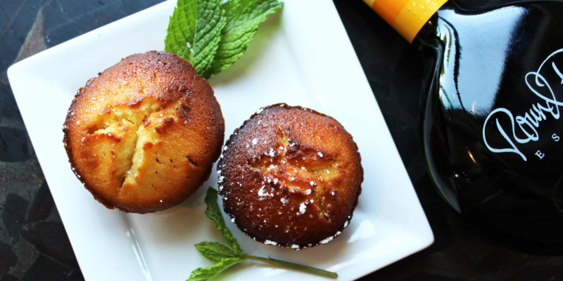 Delicious Meyer Lemon Olive Oil Cake muffins on a white plate, garnished with fresh mint leaves, with a bottle of olive oil i.