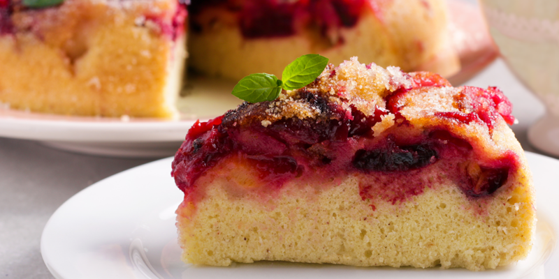 Upside Down Plum Caramel Cake with fresh fruit and caramel topping, served on a white plate.