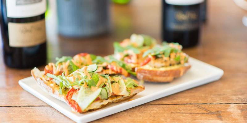 Delicious Vadouvan chicken sandwich topped with grilled lemon aioli and fresh greens on toasted bread.