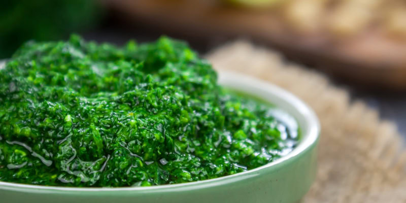 Freshly made kale pesto in a white bowl, showcasing vibrant green color and textured surface.