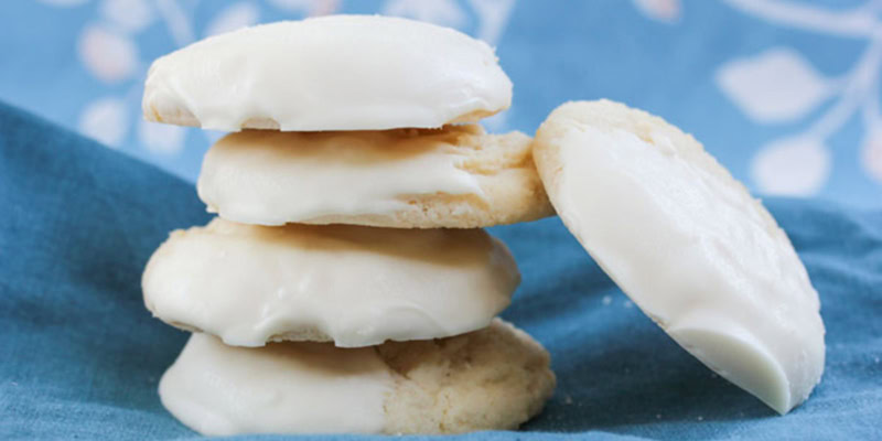 Close-up of Meyer Lemon Shortbread Cookies stacked on a blue cloth, showcasing their buttery texture and lemon flavor.