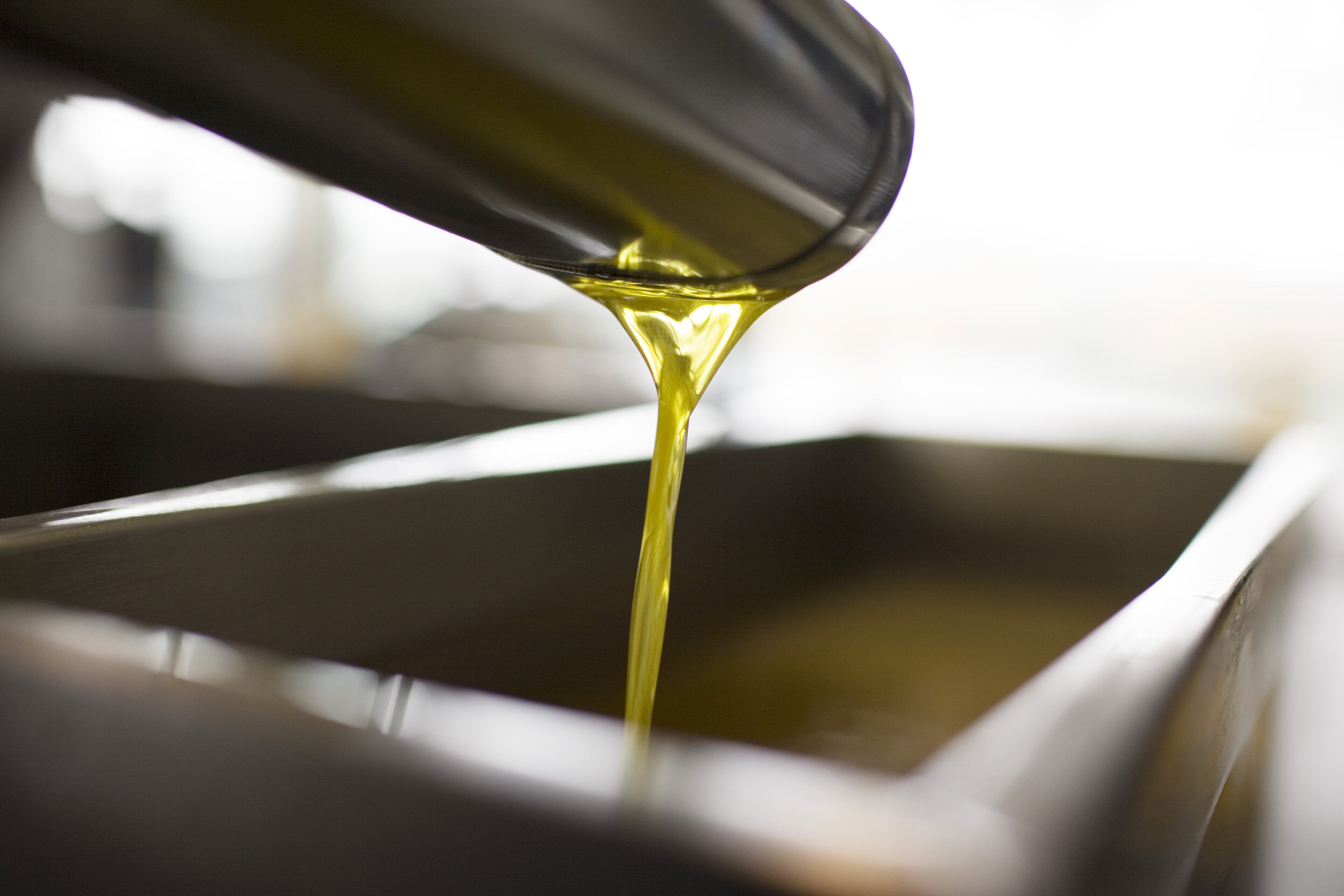 Close-up of olive oil being poured into a container at Round Pond Estate, showcasing the quality of their premium oils.